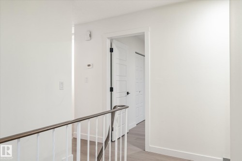 The property features a hallway with white walls, light-colored flooring, and a white railing with a dark top - 6540 184 Street, Edmonton, AB - Indoor Photo Showing Other Room