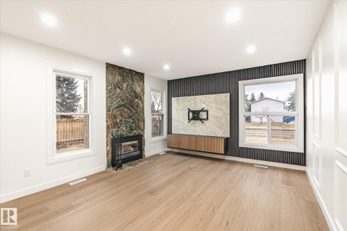 The property features hardwood floors, a stone fireplace, and paneled walls - 6540 184 Street, Edmonton, AB - Indoor With Fireplace