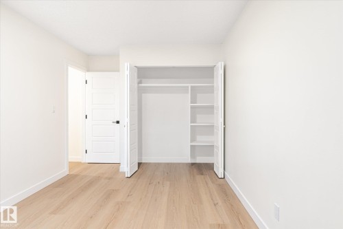 This room features light wood flooring, white walls, and a modern white door with a black handle - 6540 184 Street, Edmonton, AB - Indoor Photo Showing Other Room
