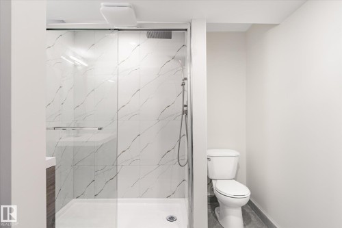 Bathroom featuring a shower with tiled walls and a glass enclosure, as well as a toilet - 6540 184 Street, Edmonton, AB - Indoor Photo Showing Bathroom