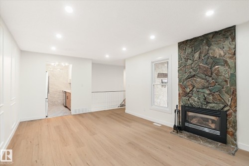 Living area featuring light wood flooring, recessed lighting, and a stone-clad fireplace with a hearth - 6540 184 Street, Edmonton, AB - Indoor With Fireplace
