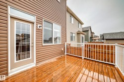 The property features a large deck with wooden planks and white railings, accessible via a glass-paneled door - 