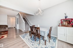 The dining area features light-colored walls, a modern ceiling light fixture, and light-toned flooring - 