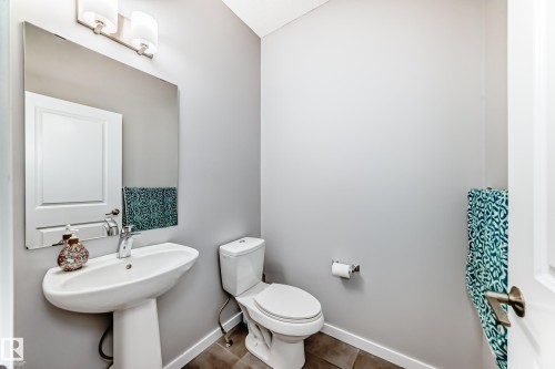 Bathroom featuring a pedestal sink with a chrome faucet, a mirror, and a toilet - 5868 Anthony Crescent, Edmonton, AB - Indoor Photo Showing Bathroom