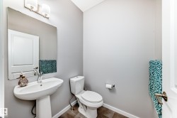 Bathroom featuring a pedestal sink with a chrome faucet, a mirror, and a toilet - 