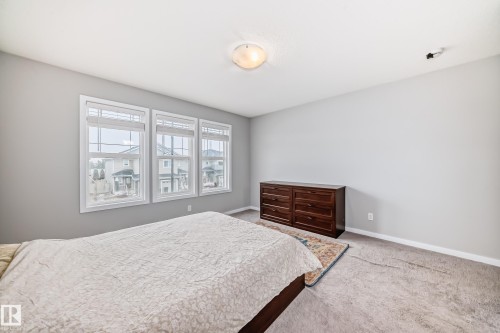 This bedroom offers ample natural light through three large windows, featuring blinds for privacy - 5868 Anthony Crescent, Edmonton, AB - Indoor Photo Showing Bedroom