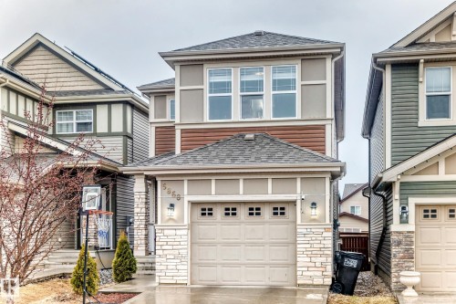 The property features a two-story design with a garage, stone facade accents, and a grey shingle roof - 5868 Anthony Crescent, Edmonton, AB - Outdoor With Facade