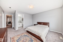 This bedroom features light gray walls, a ceiling light fixture, and carpeted flooring - 