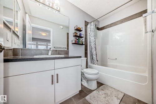 Bathroom featuring a white vanity with a dark countertop, a mirror, and a bathtub with a shower - 5868 Anthony Crescent, Edmonton, AB - Indoor Photo Showing Bathroom
