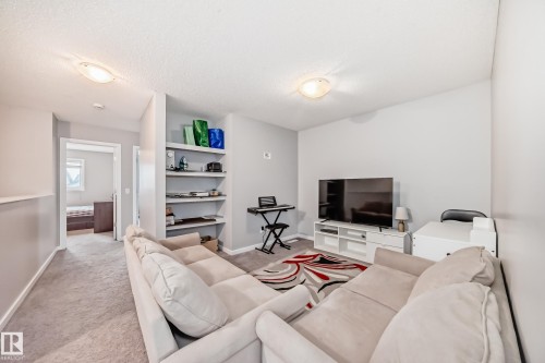 Living area with light-colored walls and carpeted flooring, featuring built-in shelving, and recessed lighting - 5868 Anthony Crescent, Edmonton, AB - Indoor Photo Showing Living Room