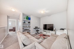 Living area with light-colored walls and carpeted flooring, featuring built-in shelving, and recessed lighting - 