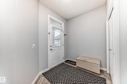 The entrance features a white door with a window, light gray walls, and light-colored flooring - 