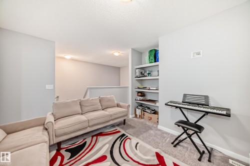 Carpeted living area featuring built-in shelving, a neutral color palette, and recessed lighting - 5868 Anthony Crescent, Edmonton, AB - Indoor