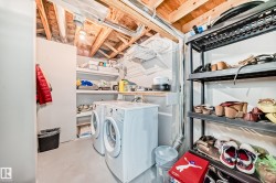 Utility room with exposed wooden beams, a washer and dryer, and built-in shelving - 