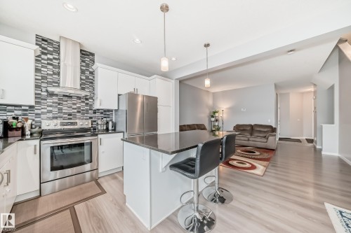The kitchen features white cabinetry, stainless steel appliances, a dark countertop, and a tiled backsplash - 5868 Anthony Crescent, Edmonton, AB - Indoor Photo Showing Kitchen With Upgraded Kitchen