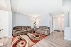 The living area features light-colored walls, light wood-look flooring, and a partial view of a white door - 