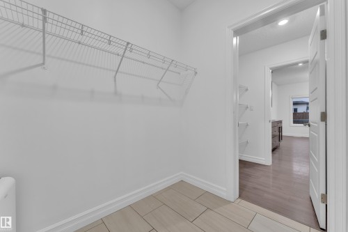 This space features wire shelving, light-toned floor tiling, and white baseboards - 3235 13 Avenue, Edmonton, AB - Indoor With Storage