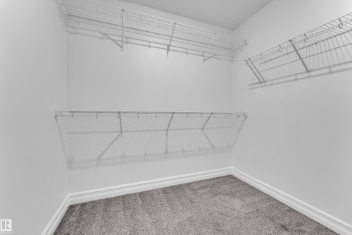 This closet features a neutral color palette, grey carpeting, and white wire shelving, offering practical storage solutions - 3235 13 Avenue, Edmonton, AB - Indoor With Storage