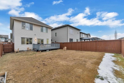 The property features a fenced backyard with a wooden deck, a spacious lawn, and a two-story exterior with horizontal siding - 3235 13 Avenue, Edmonton, AB - Outdoor With Deck Patio Veranda With Exterior