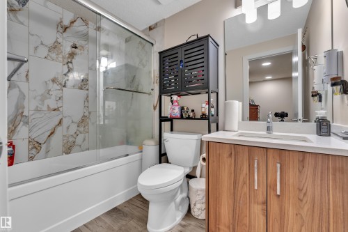 The bathroom features a bathtub with a glass sliding shower door and marble-patterned wall tiles - 3235 13 Avenue, Edmonton, AB - Indoor Photo Showing Bathroom
