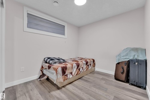 The room features light gray walls, a window with horizontal blinds, and wide plank flooring - 3235 13 Avenue, Edmonton, AB - Indoor Photo Showing Bedroom