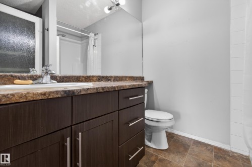 Bathroom featuring a dark wood vanity with a light-colored countertop, a white toilet, and tiled flooring - 131 2098 Blackmud Creek Drive Sw, Edmonton, AB - Indoor Photo Showing Bathroom