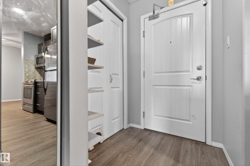 Entryway featuring wood-style flooring, a white paneled door with chrome hardware, and a built-in shelving unit - 131 2098 Blackmud Creek Drive Sw, Edmonton, AB - Indoor Photo Showing Other Room