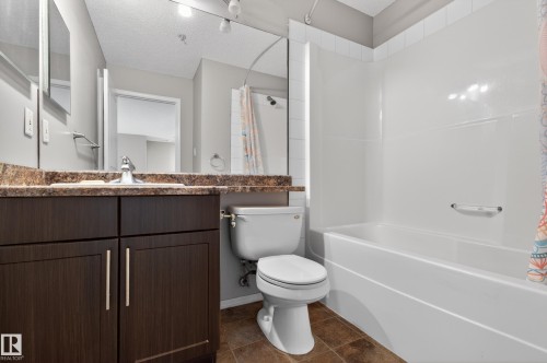Bathroom featuring a dark wood vanity with a light-colored countertop, a white toilet, and a bathtub with a white surround - 131 2098 Blackmud Creek Drive Sw, Edmonton, AB - Indoor Photo Showing Bathroom