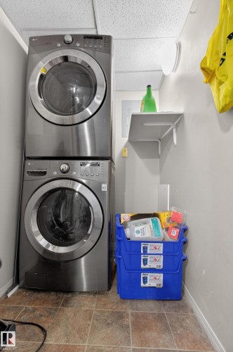 Laundry area featuring a stackable washer and dryer, tile flooring, and a wall-mounted shelf - 131 2098 Blackmud Creek Drive Sw, Edmonton, AB - Indoor Photo Showing Laundry Room