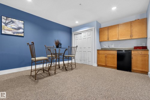 This versatile room features plush carpeting, a vibrant blue accent wall, and recessed lighting - 131 2098 Blackmud Creek Drive Sw, Edmonton, AB - Indoor