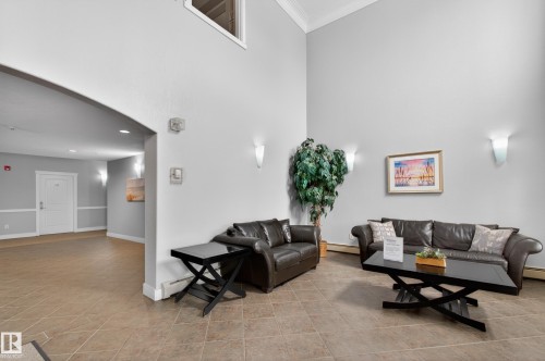 The property features a reception area with high ceilings, tiled floors, and dark leather seating - 131 2098 Blackmud Creek Drive Sw, Edmonton, AB - Indoor