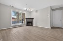 Living area featuring light-toned flooring, a corner fireplace, and a sliding glass door leading to a balcony - 131 2098 Blackmud Creek Drive Sw, Edmonton, AB  - Indoor Photo Showing Living Room With Fireplace 