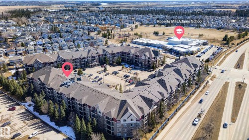 Aerial view showcasing the property's exterior, including its multi-story design and ample parking areas - 131 2098 Blackmud Creek Drive Sw, Edmonton, AB - Outdoor With View