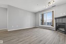 Living area featuring wood-look flooring, light grey walls, and a fireplace with a dark mantel - 131 2098 Blackmud Creek Drive Sw, Edmonton, AB  - Indoor With Fireplace 