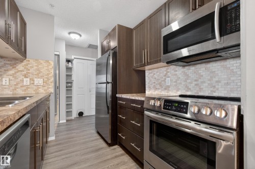 The kitchen features wood cabinets, stainless steel appliances, and a tiled backsplash - 131 2098 Blackmud Creek Drive Sw, Edmonton, AB - Indoor Photo Showing Kitchen With Stainless Steel Kitchen With Upgraded Kitchen