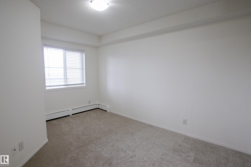 This room features light-colored carpeting, white walls, and a window with blinds - 405 534 Watt Boulevard, Edmonton, AB - Indoor Photo Showing Other Room
