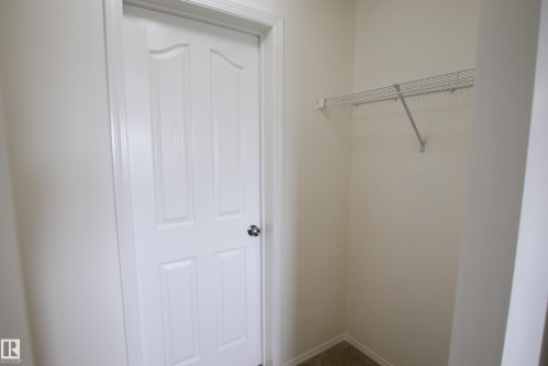 The property features a closet with a wire shelf, carpeted flooring, and a white paneled door with a polished doorknob - 405 534 Watt Boulevard, Edmonton, AB - Indoor
