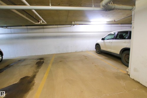 Underground parking space with concrete flooring and exposed piping - 405 534 Watt Boulevard, Edmonton, AB - Indoor Photo Showing Garage