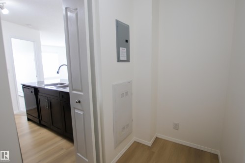 Kitchen area featuring dark cabinetry, a double basin sink with a high-arc faucet, and a dishwasher - 405 534 Watt Boulevard, Edmonton, AB - Indoor