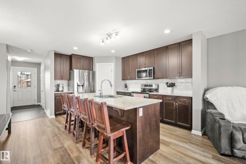 The kitchen features wood plank flooring, dark wood cabinetry, stainless steel appliances, and a central island with a light-colored countertop - 635 41 Avenue, Edmonton, AB - Indoor Photo Showing Kitchen With Upgraded Kitchen