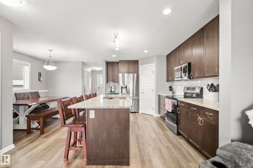 The kitchen features dark wood cabinetry, stainless steel appliances, and a light-colored countertop - 635 41 Avenue, Edmonton, AB - Indoor Photo Showing Kitchen With Upgraded Kitchen