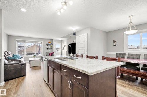 Open concept living space featuring a kitchen island with a granite countertop, a dining area with ample seating, and large windows providing natural light - 635 41 Avenue, Edmonton, AB - Indoor