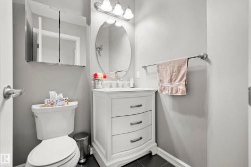 Bathroom featuring a white vanity with drawers, an oval mirror, and a toilet - 635 41 Avenue, Edmonton, AB - Indoor Photo Showing Bathroom