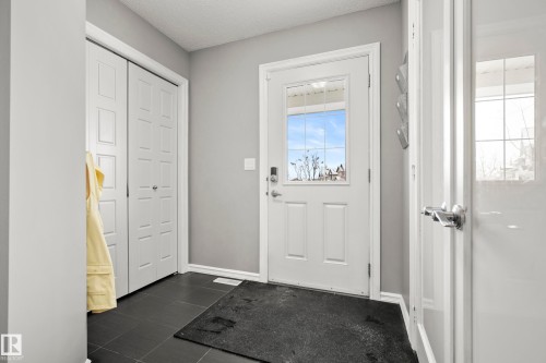 The property entrance features dark tile flooring, a white front door with a window, and a closet with bifold doors - 635 41 Avenue, Edmonton, AB - Indoor Photo Showing Other Room