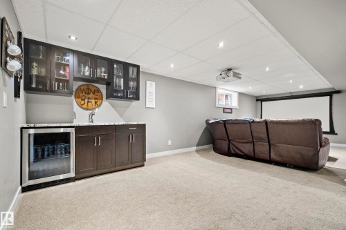 Recreational space featuring a built-in wet bar with dark cabinetry, a beverage refrigerator, and a projection screen - 635 41 Avenue, Edmonton, AB - Indoor