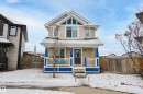 The property features a charming exterior with light-colored siding, a front porch with blue accents and white railings, and a dark front door with window inserts - 635 41 Avenue, Edmonton, AB  - Outdoor With Deck Patio Veranda 