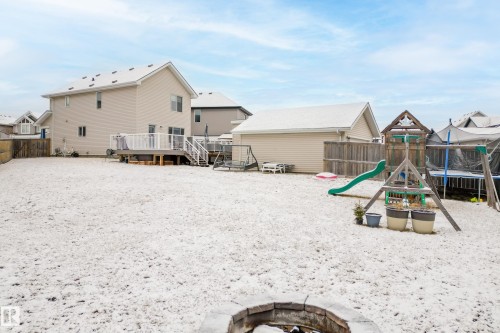 Expansive backyard with a snow-covered lawn, a wood deck with railings and stairs, and a stone fire pit - 635 41 Avenue, Edmonton, AB - Outdoor With Deck Patio Veranda