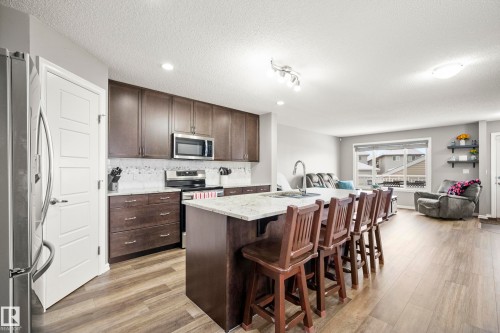 The kitchen features granite countertops, dark wood cabinetry, a stainless steel refrigerator, and a stainless steel oven/range with a microwave - 635 41 Avenue, Edmonton, AB - Indoor Photo Showing Kitchen