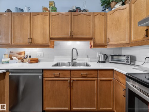 The kitchen features wood cabinetry, white countertops, and a white subway tile backsplash - 7 85 Gervais Road, St. Albert, AB - Indoor Photo Showing Kitchen With Double Sink
