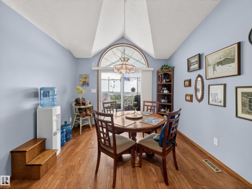 Dining area featuring vaulted ceilings, a large arched window, and wood flooring - 7 85 Gervais Road, St. Albert, AB - Indoor Photo Showing Dining Room